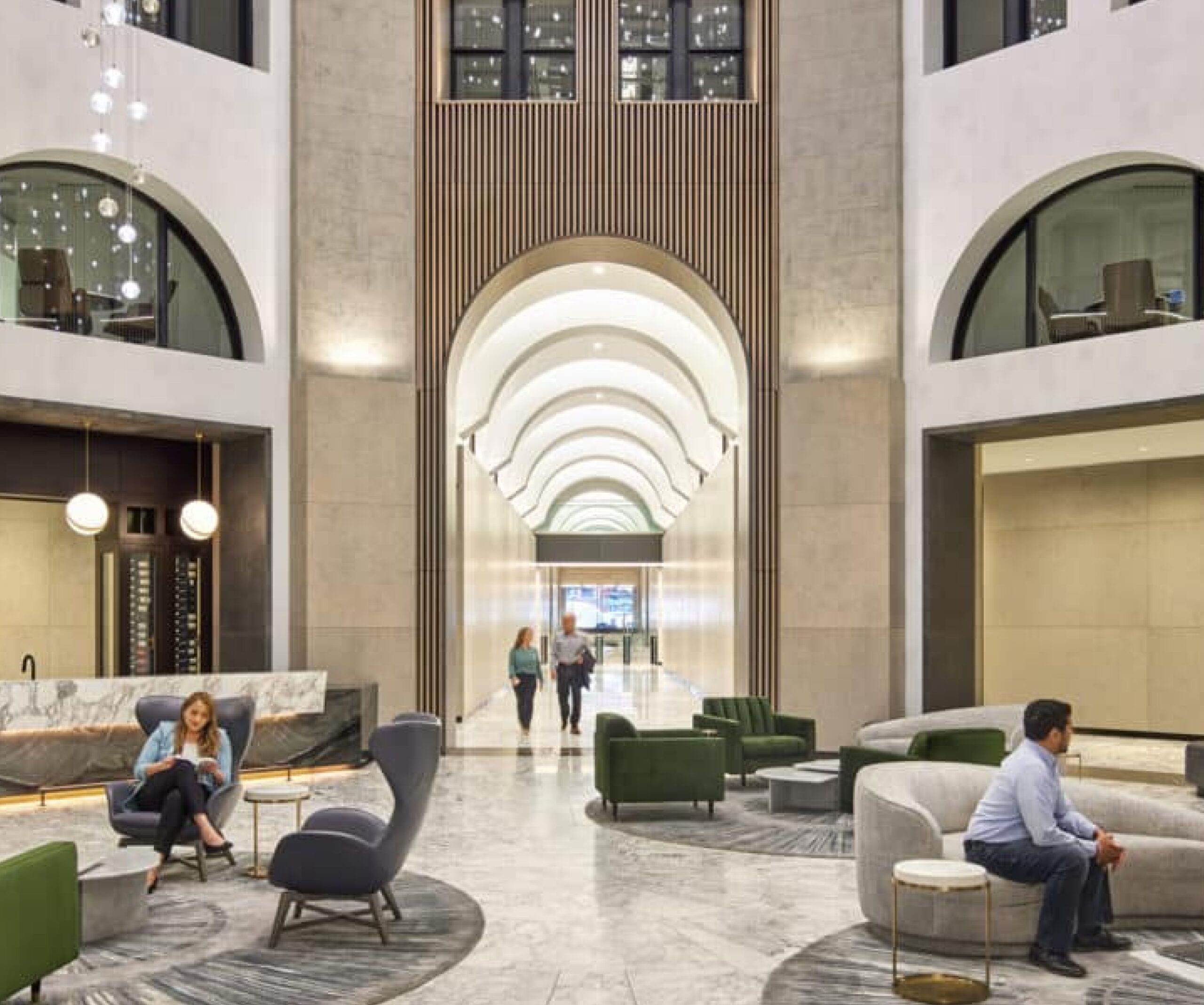An office lobby concept with high ceilings. Two people sit on chairs while two others walk in from the hallway.
