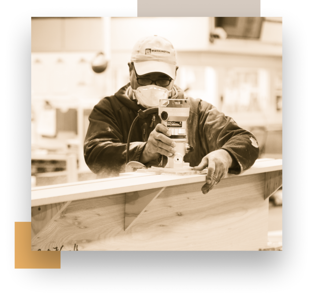 A man in a Washington Woodworking cap cuts a slab of wood